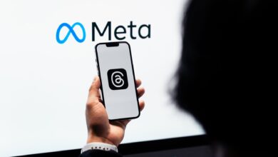 Hands holding smartphone with Meta Threads logo on screen, Meta branding in background.