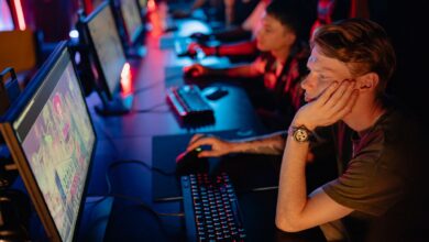 Gamers intensely focused on a computer game during an online esport competition in a dimly lit arena.