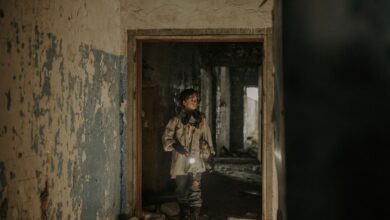 A young man exploring an abandoned building with a flashlight, showcasing urban decay and survival themes.