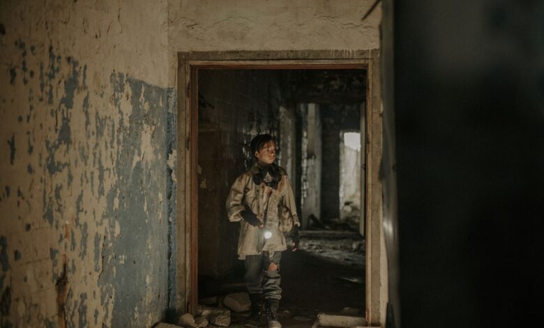 A young man exploring an abandoned building with a flashlight, showcasing urban decay and survival themes.