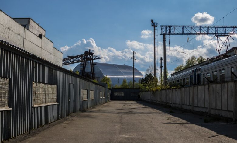 View of Chernobyl's new safe confinement and railway tracks under a blue sky.