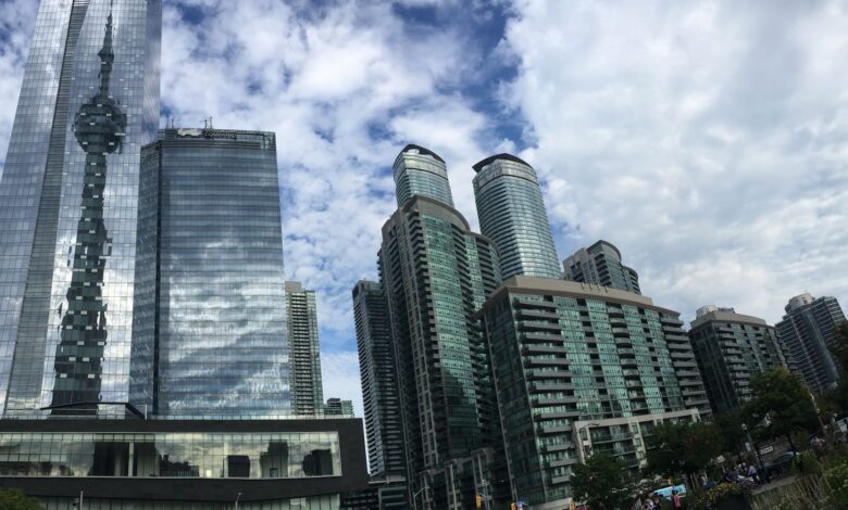 A stunning view of Toronto's modern skyline reflecting the iconic CN Tower on a bright day.