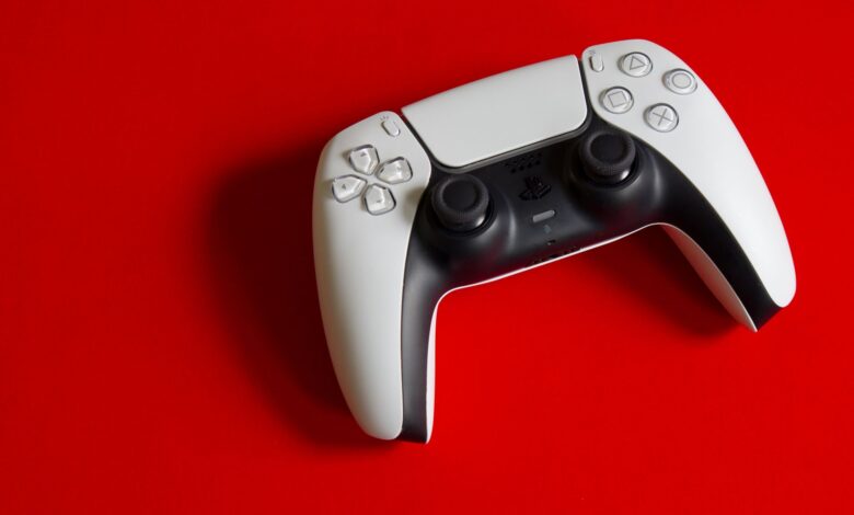 White DualSense controller for PlayStation 5 on a striking red backdrop, emphasizing modern gaming technology.