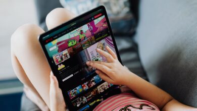 A child using a tablet for streaming cartoons, relaxing on a couch indoors.