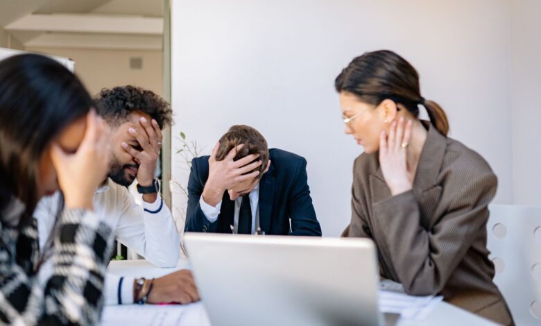 A group of stressed business professionals in an office setting, overwhelmed by work.