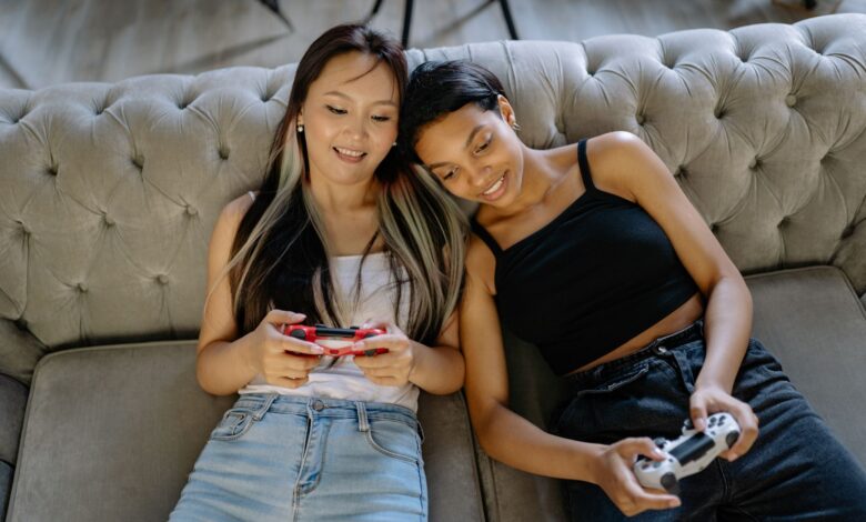 Two women relaxing and playing video games on a comfortable sofa together.