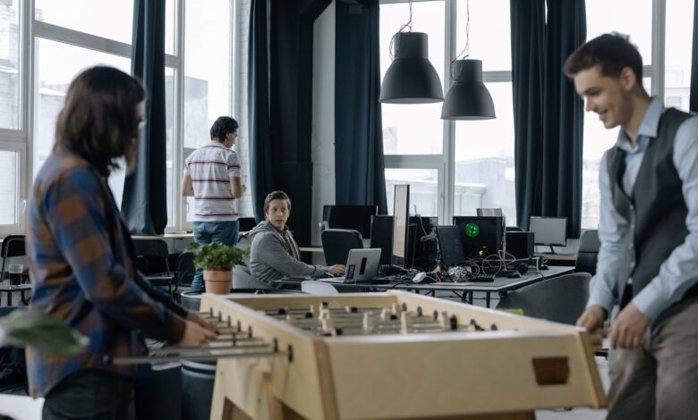 A modern office environment featuring a foosball table with employees engaging in teamwork.