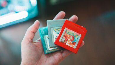 Hand holding vintage Pokemon game cartridges, showcasing nostalgic gaming.