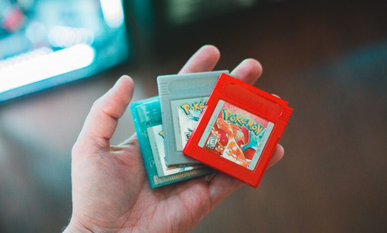 Hand holding vintage Pokemon game cartridges, showcasing nostalgic gaming.