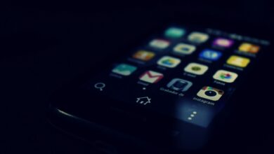 Dark-themed close-up of a smartphone screen highlighting various apps and touchscreen technology.