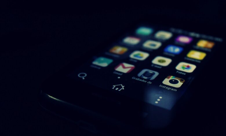 Dark-themed close-up of a smartphone screen highlighting various apps and touchscreen technology.