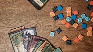 Top view of colorful board game cards and tokens on a wooden table, suggesting playful entertainment.