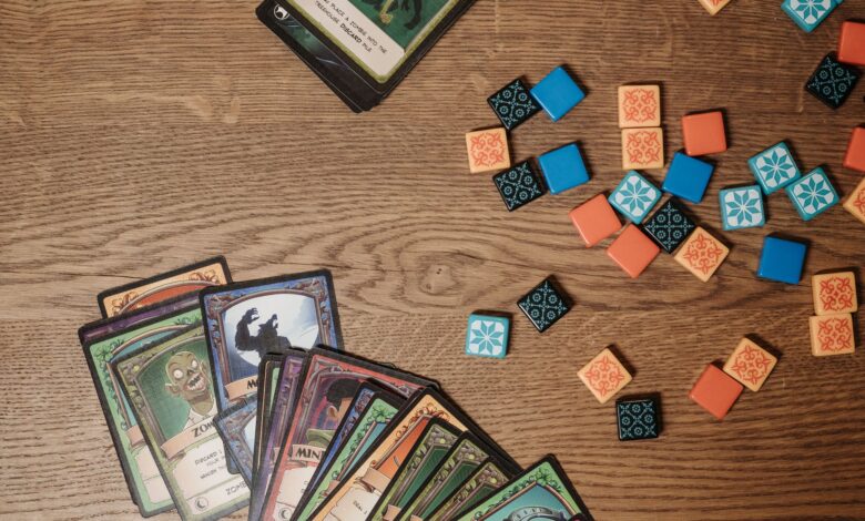 Top view of colorful board game cards and tokens on a wooden table, suggesting playful entertainment.