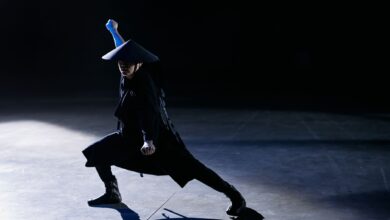 A skilled cosplayer strikes a dramatic pose as a game character in a dark studio setting.