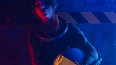 A woman astronaut in a spacesuit under vibrant red and blue lighting, evoking a futuristic, sci-fi atmosphere.