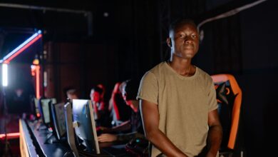A young gamer in a dimly lit gaming arena, surrounded by teammates.
