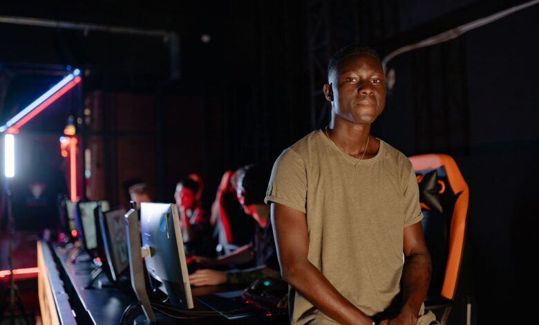 A young gamer in a dimly lit gaming arena, surrounded by teammates.