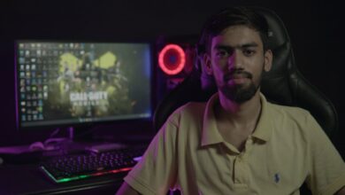 A bearded man sitting at a computer setup with a gaming PC and chair, creating a moody ambiance.