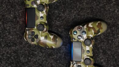 Close-up view of camouflage-patterned game controllers on a dark carpet background.
