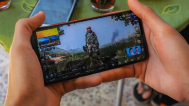 From above crop anonymous male playing captivating video game on contemporary mobile phone near table on terrace