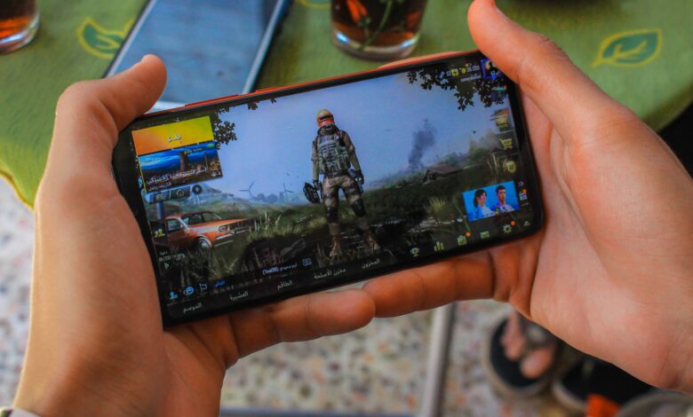 From above crop anonymous male playing captivating video game on contemporary mobile phone near table on terrace