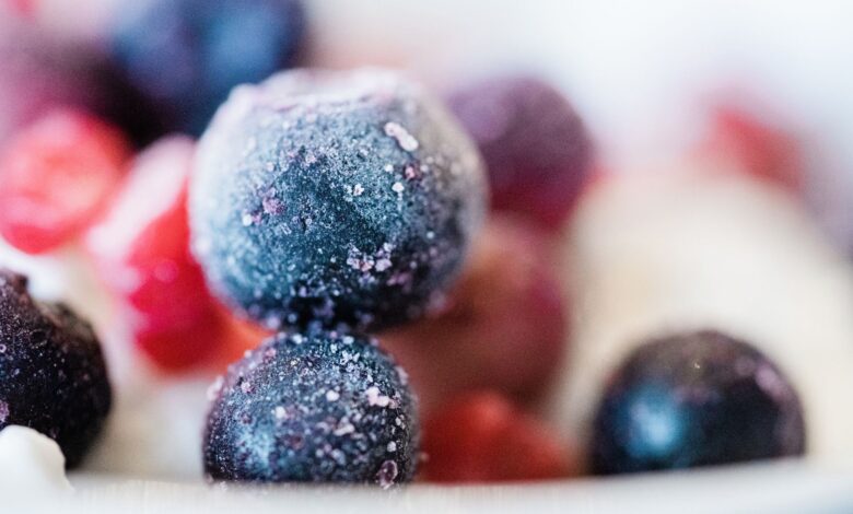 Frozen blueberries and fruits in a close-up shot, showcasing frost and vibrant colors.