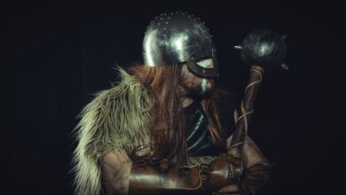 Viking warrior in medieval armor holding a mace, with fur cloak and metal helmet.