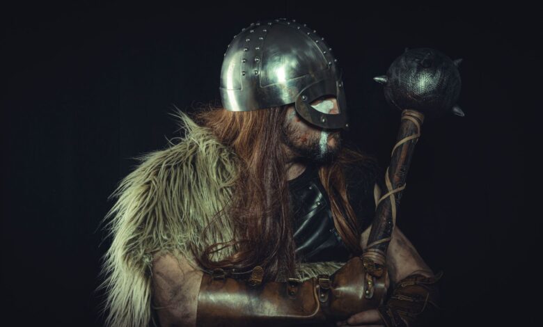 Viking warrior in medieval armor holding a mace, with fur cloak and metal helmet.