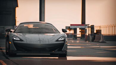 Elegant supercar with wet reflections parked on an urban street, showcasing modern design under a muted sky.