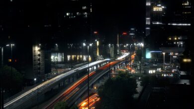 Night view of a bustling highway in Warsaw, Poland, featuring light trails and urban skyscrapers.