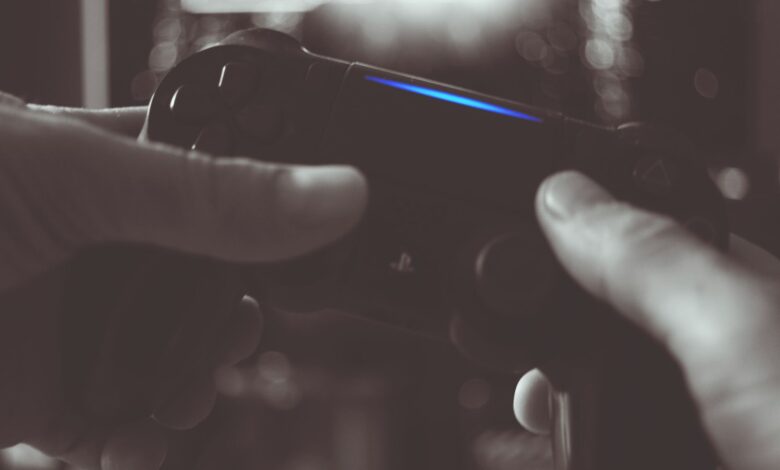 Close-up of hands gripping a gaming controller in dim light, emphasizing electronic entertainment.