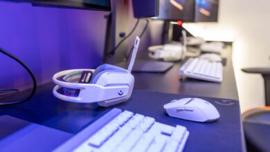 Close-up of a gaming setup featuring a white headset, computer mouse, and keyboard with a vivid lighting ambiance.