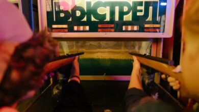 Teenagers having fun playing a vintage arcade shooting game with rifles at an amusement park arcade.