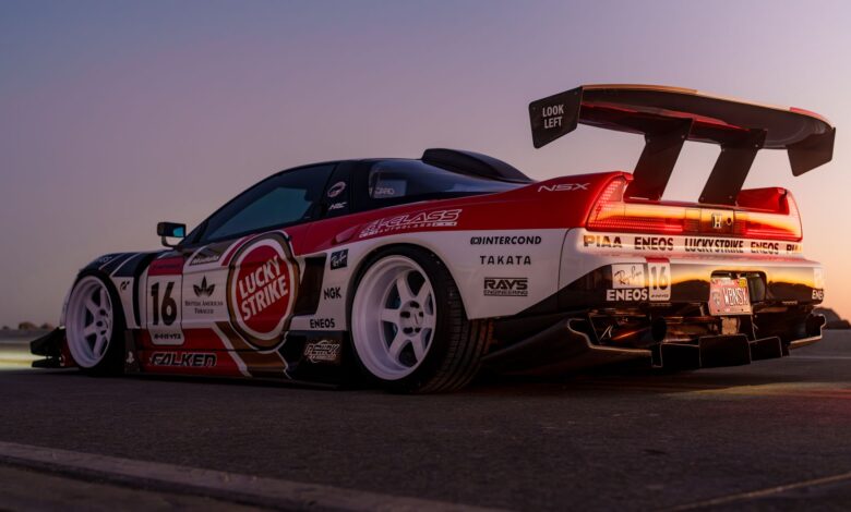 A sleek racing car with vibrant decals parked outdoors at sunset, showcasing racing culture.