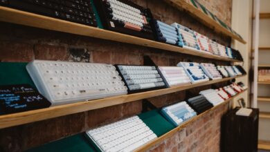 A variety of mechanical keyboards neatly displayed on a shelf in a brick-walled store interior.