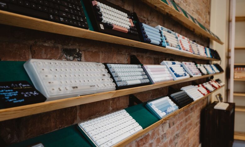 A variety of mechanical keyboards neatly displayed on a shelf in a brick-walled store interior.