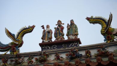 Colorful rooftop sculptures of deities and dragons on a traditional temple, showcasing artistic craftsmanship.