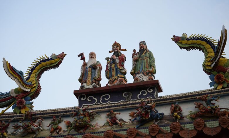 Colorful rooftop sculptures of deities and dragons on a traditional temple, showcasing artistic craftsmanship.