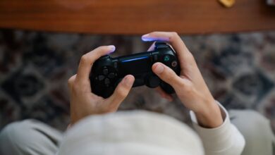From above of crop unrecognizable male with console controller playing video game in living room