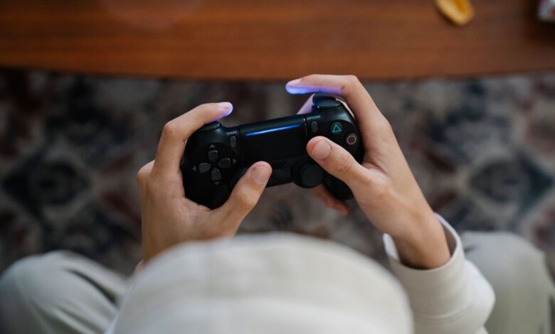 From above of crop unrecognizable male with console controller playing video game in living room