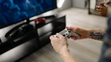 Person playing video games using a game controller indoors on a modern TV setup.