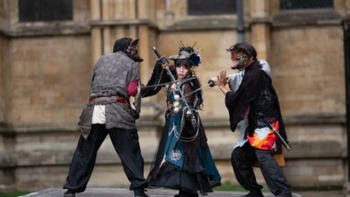 Intense cosplay battle with swords in a medieval outdoor setting.