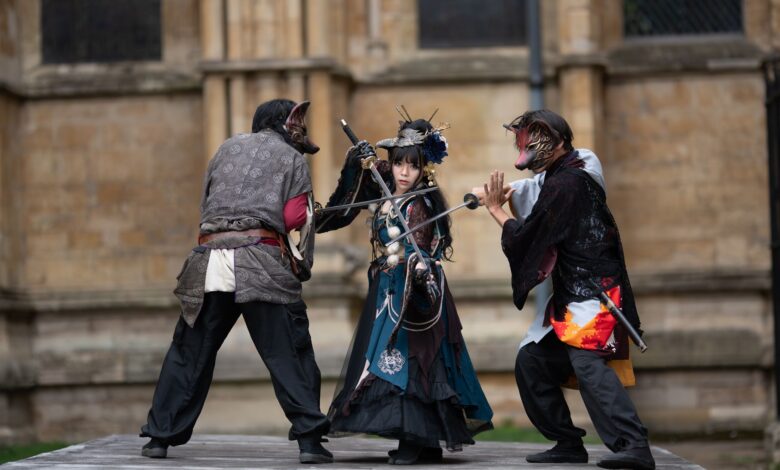 Intense cosplay battle with swords in a medieval outdoor setting.