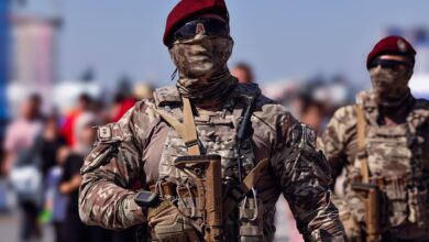 Armed Turkish commandos in camouflage gear marching outdoors during the day.