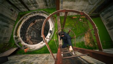Man ascends a rusty ladder inside an abandoned industrial site. Urban exploration vibe.
