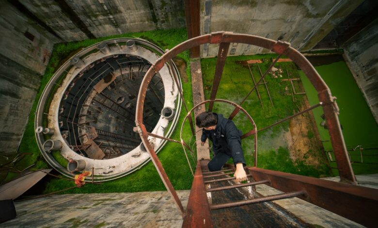 Man ascends a rusty ladder inside an abandoned industrial site. Urban exploration vibe.