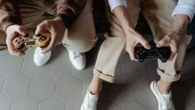 Two adults playing video games with controllers while seated on a sofa, having fun indoors.