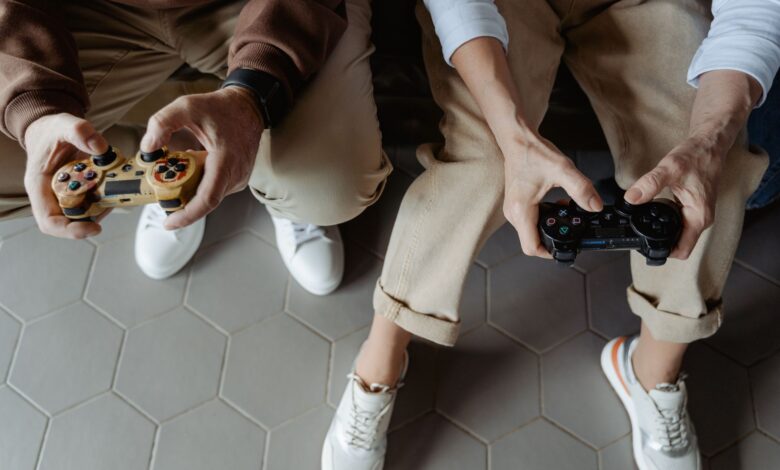 Two adults playing video games with controllers while seated on a sofa, having fun indoors.