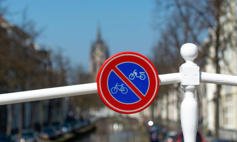 A no bicycles sign on a bridge in Delft, the Netherlands, by a canal on a sunny day.