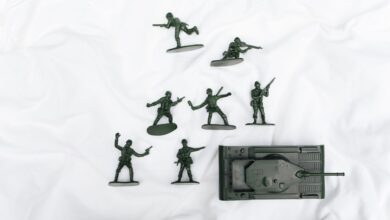 Green plastic toy soldiers and tank arranged on a white backdrop.